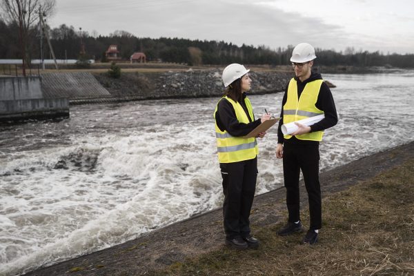 full-shot-engineers-standing-near-river full-shot-engineers-standing-near-river